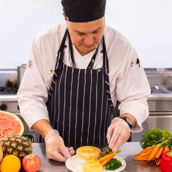 Image of chief putting together a plate of food.